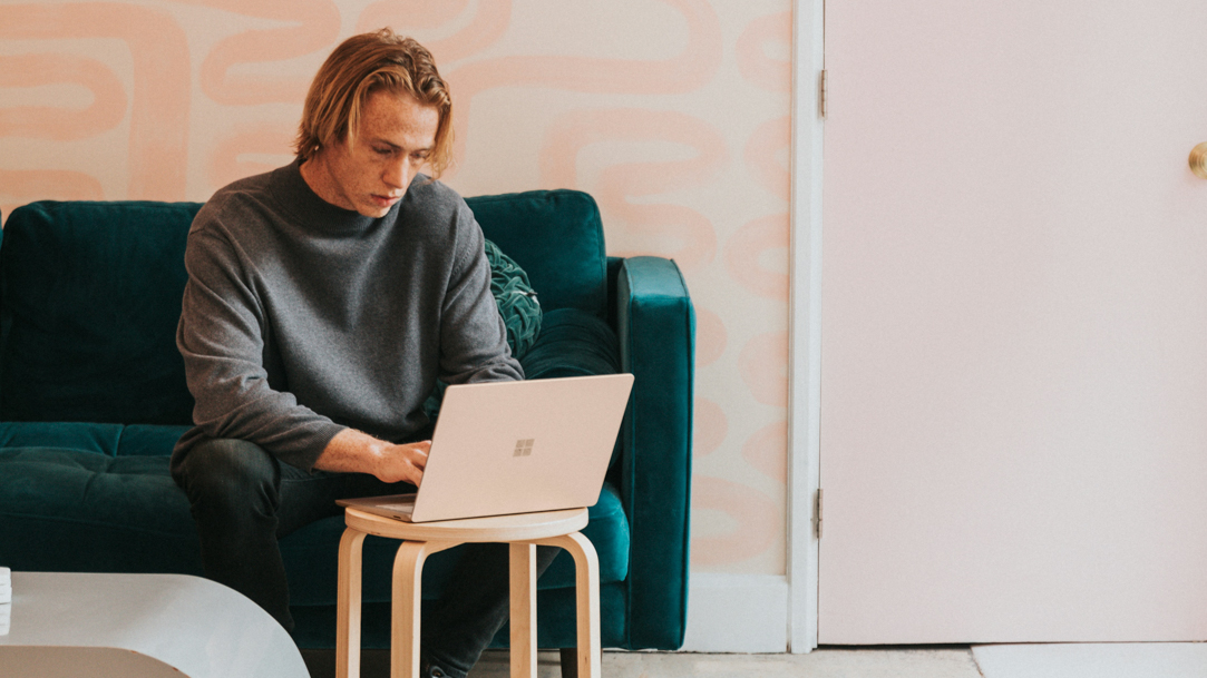 Man sitting on a sofa using a Surface device