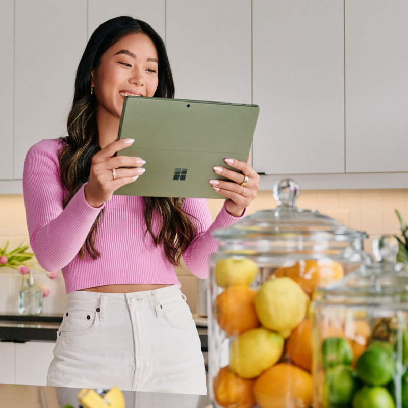  A smiling woman standing in a kitchen looking at a PC