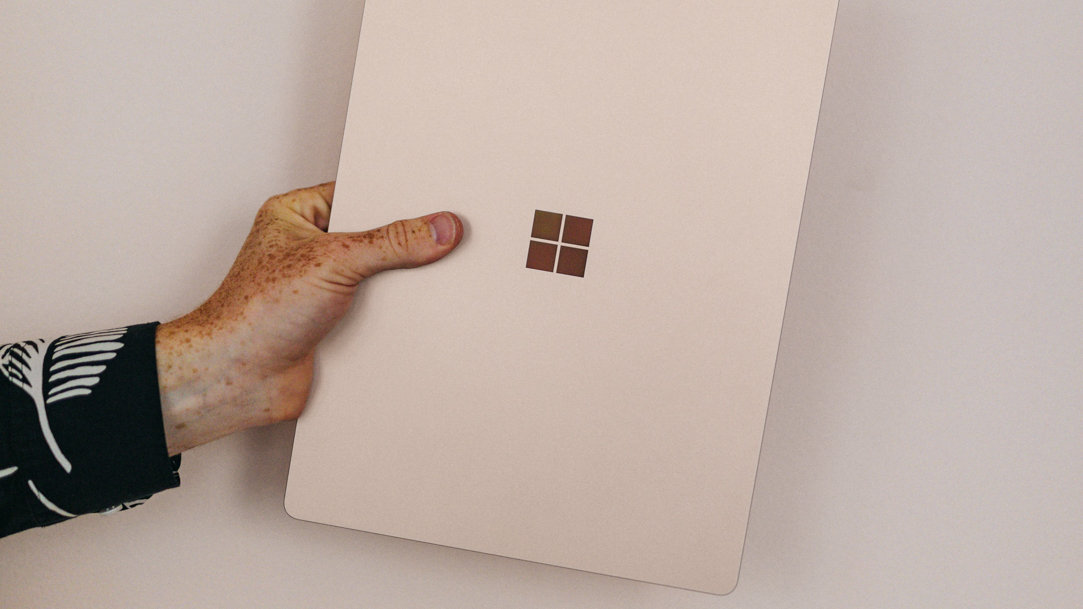 Person holding a closed Surface laptop