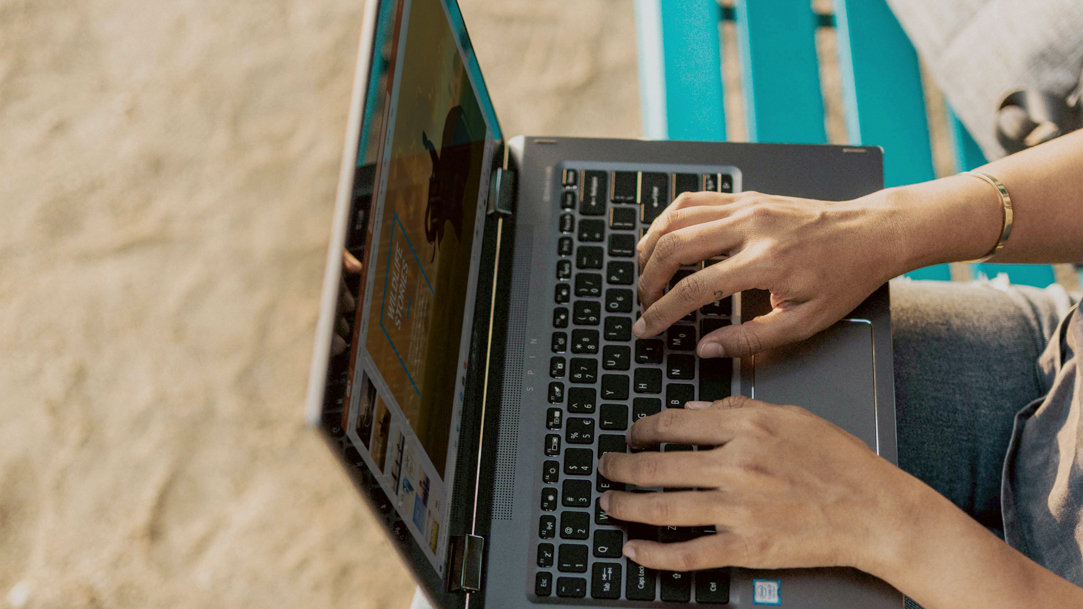 Person using Windows laptop while sitting on a bench