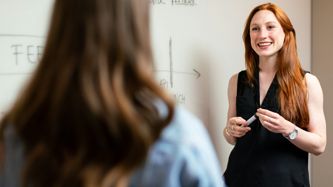 Teacher talking to a student in front of a whiteboard