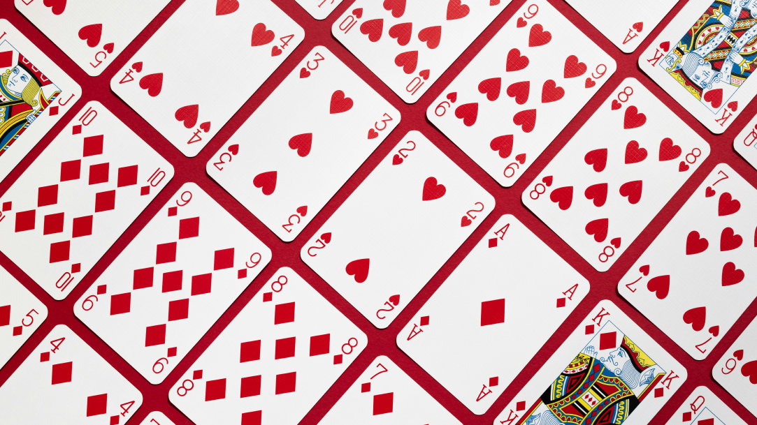 The hearts and diamonds from a pack of playing cards arranged diagonally against a red background