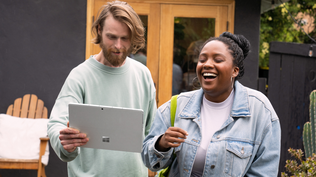 Two people using a Surface Pro 9 with 5G while outside