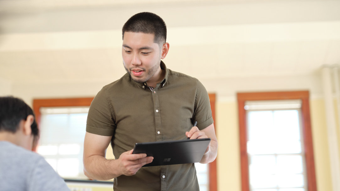 Two people using a Surface pen to draw on the screen of a Microsoft Surface 2-in-1 PC