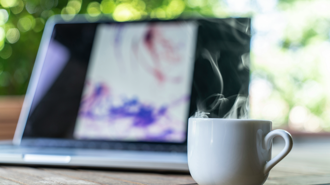 White ceramic mug near a laptop outside