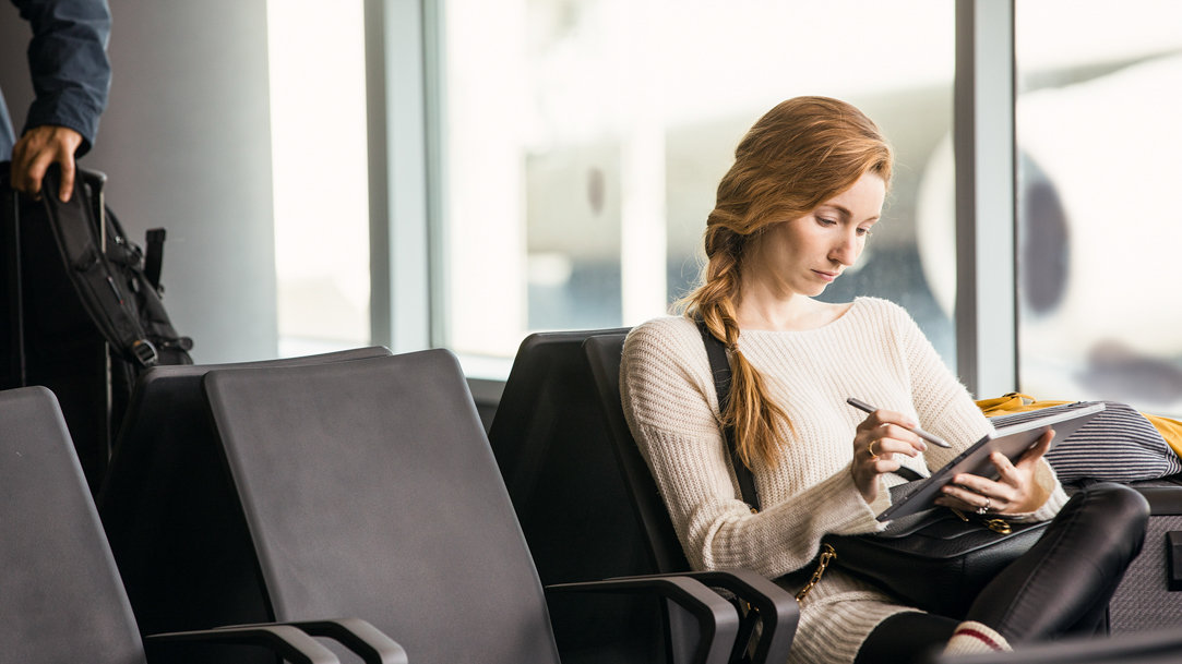 Woman at the airport using Surface device and pen