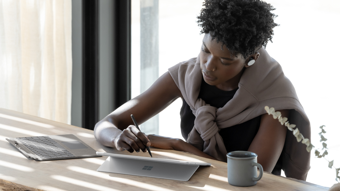 Woman sitting at a table using her Surface Pro 11ᵗʰ Edition