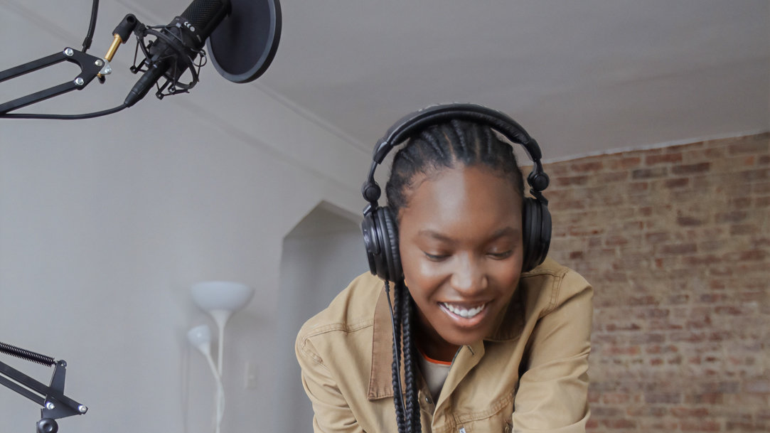 Woman with headphones and mic set using a Microsoft Surface laptop