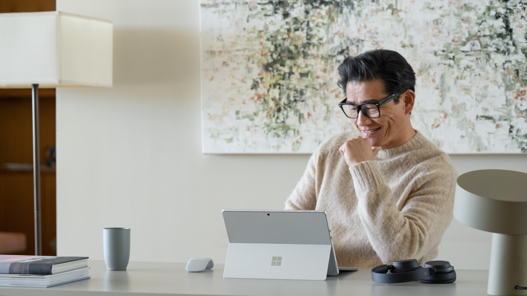 man in cream long sleeve shirt using Surface at home