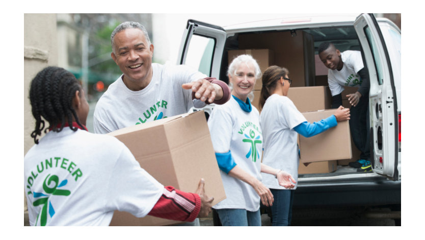 Group of volunteers passing cardboard boxes from delivery van