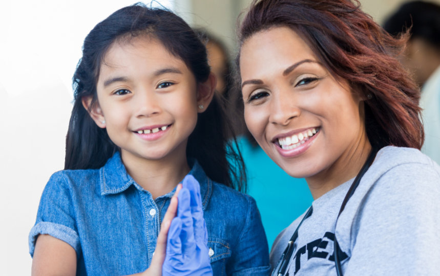 Kid and volunteer smiling at the camera.