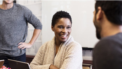 Three people smiling in a workspace.