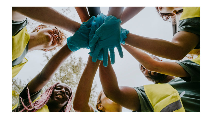 A group of volunteers standing in a circle and putting their hands together.