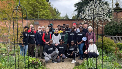 A group of volunteers posing along with church members in a garden.