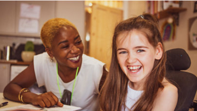 An adult and a child smile inside a room.