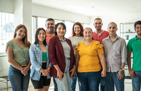 A team of nine, diverse coworkers smiling at the camera.