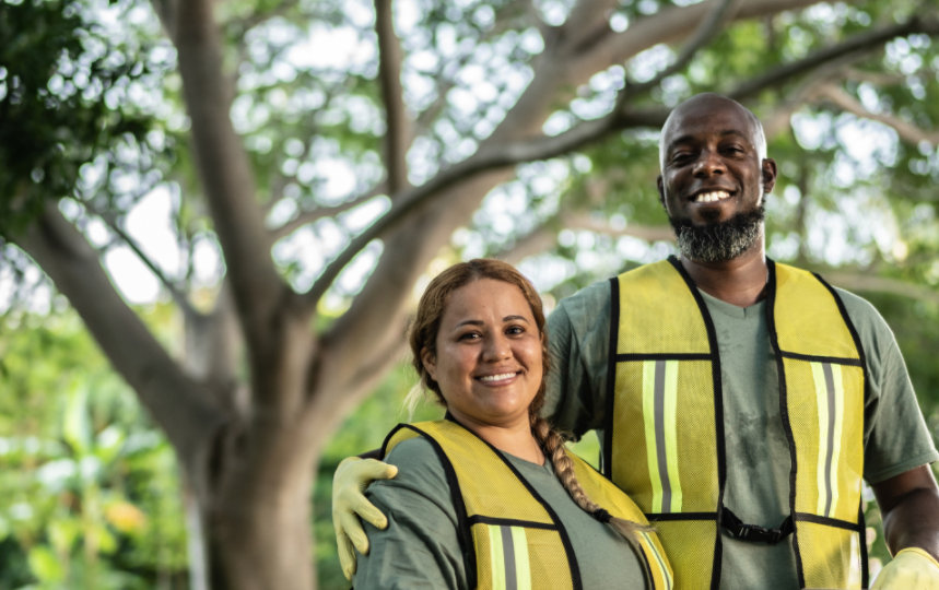 A volunteer couple smiles at a public park.