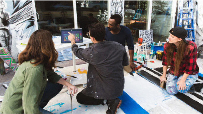 A group of artists looking at a laptop.