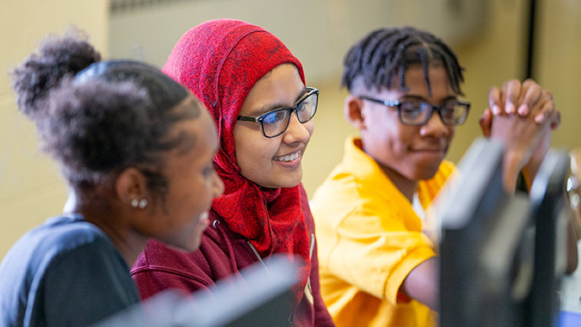 Three diverse students sitting around a computer