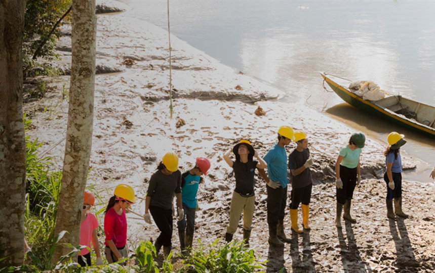 A line of people in hardhats prepares to unload a boat