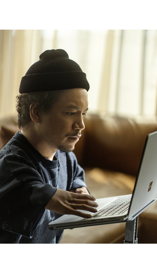 Young man wearing a beanie interacts with the keyboard on his Surface Laptop Studio 2.