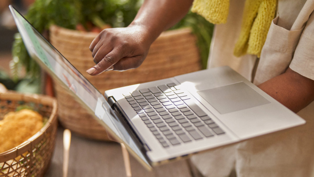 A person holding a laptop using touchscreen gestures