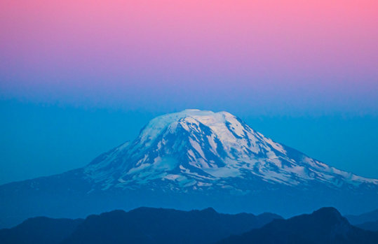 Mount Rainier in Washington State, USA, snowcapped and showing pastel bands of color at dusk.