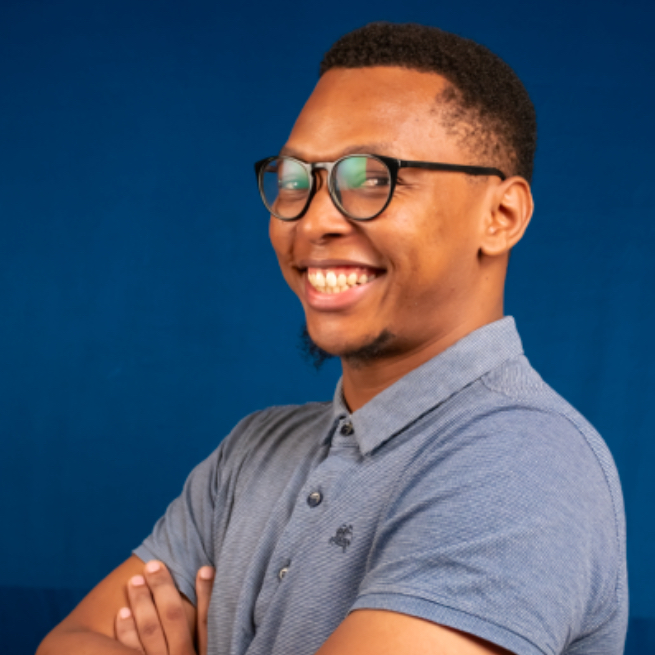 A smiling man wearing glasses and a blue shirt.