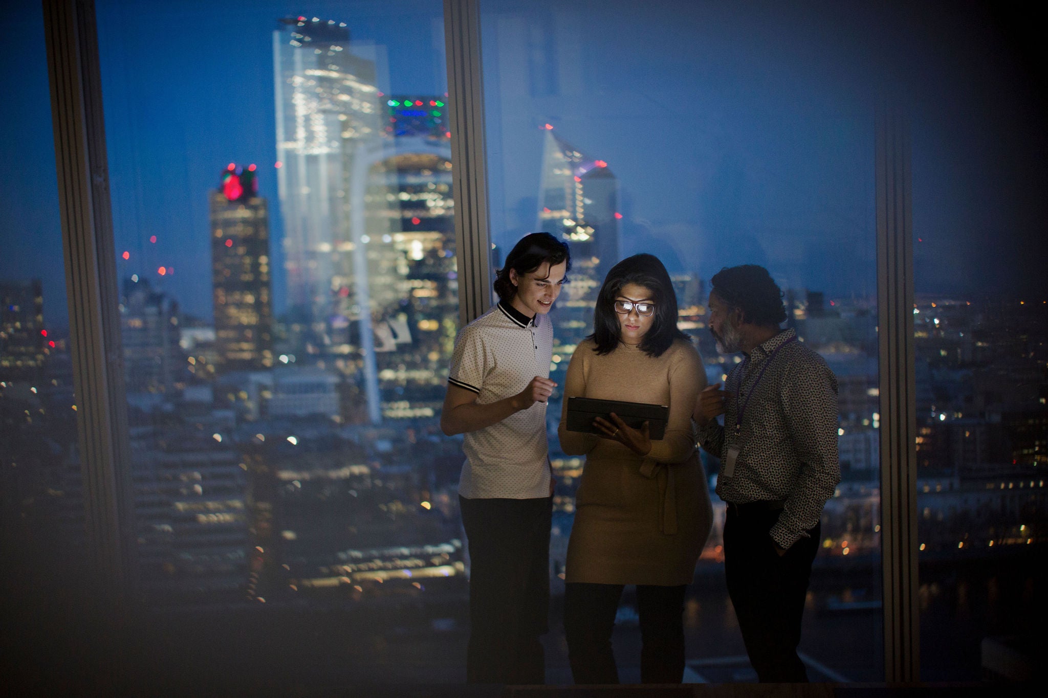 Business people with digital tablet working late at highrise window