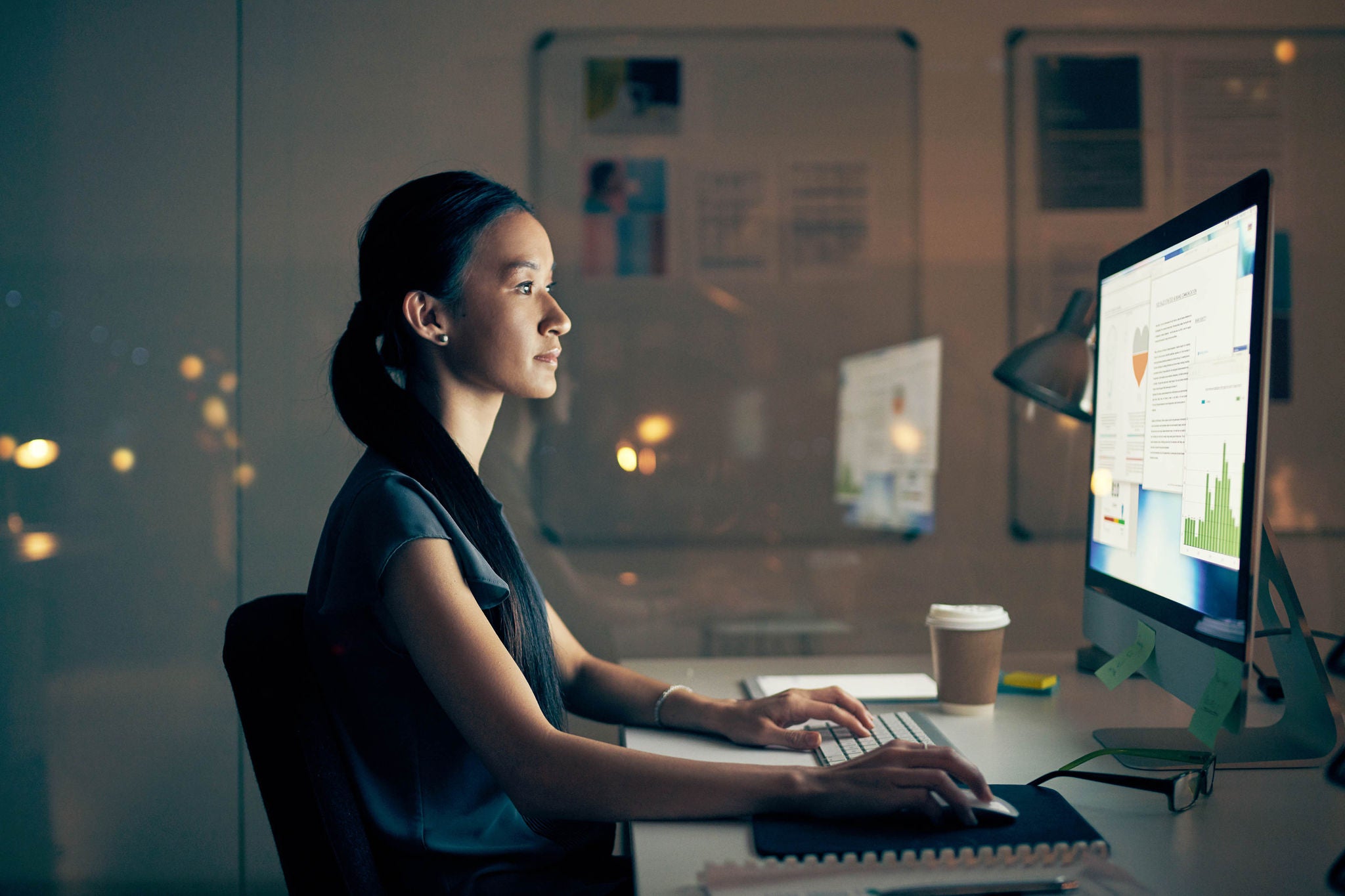 Shot of a young businesswoman using a computer at night in a modern office