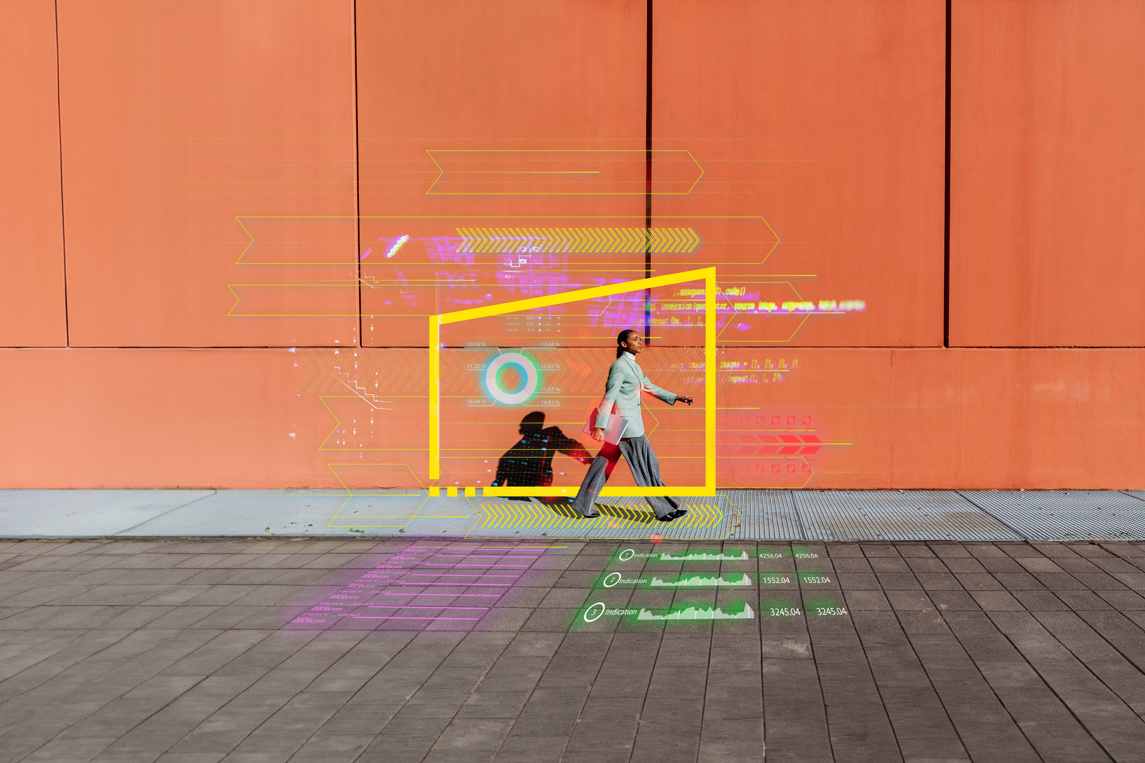 Young businesswoman with laptop walking by orange wall