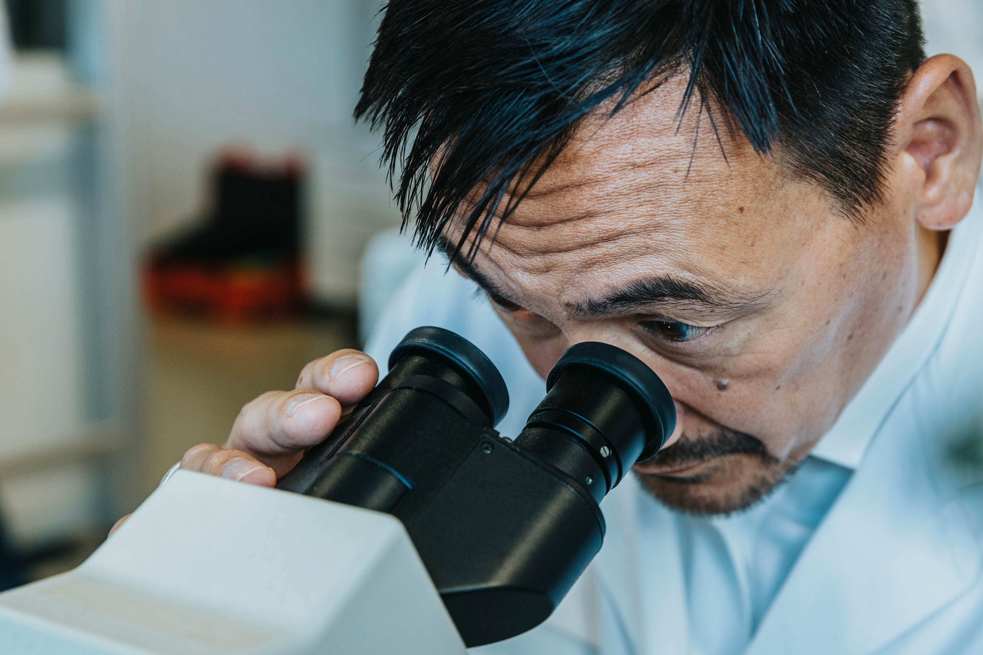 Male scientist looking though a microscope