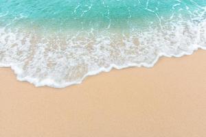 Summer beach concept of an ocean wave on empty sandy beach photo