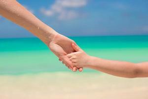 padre e hijo tomados de la mano en la playa foto