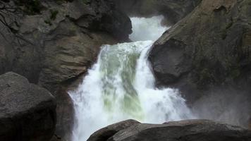 uma cachoeira jorra sobre grandes pedras video