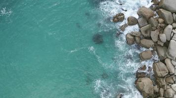 Aerial shot of deep blue ocean water and foamy waves. sea waves crash on the rocks of the coast creating an explosion of water video