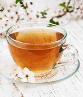 Cup of tea and spring apricot blossoms on a wooden background photo