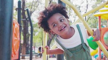 bonito menino afro-americano se divertindo enquanto brincava no playground durante o dia no verão. video