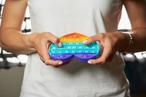 Close-up photo of a toy Pop it in the shape of a heart in the hands of a girl