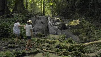 mãe e filha caminhando para ver a cachoeira na floresta tropical. video