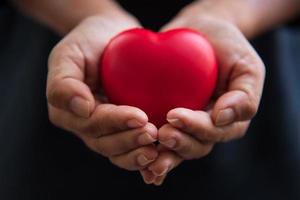 Cerrar las manos dando corazón rojo como donante de corazón foto