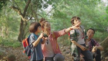 pais asiáticos trazem dois filhos, caminhando com binóculos para estudar, aprendendo sobre a natureza nas férias no centro de estudos da natureza. video