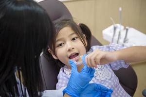 Female dentist showing invisalign to a little girl in dental clinic, teeth check-up and Healthy teeth concept photo