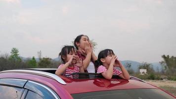 família feliz aproveitando a viagem nas férias de verão. mãe e filho curtindo a natureza ao longo do caminho no carro no teto solar. conceito de família de férias e viagens. video