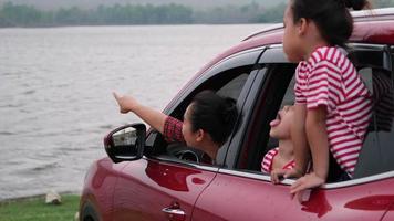 família feliz aproveitando a viagem nas férias de verão. mãe e filhos estão animados e gostam de viajar de carro e olhar pela janela. conceito de família de férias e viagens. video