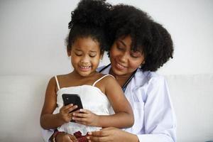 madre de raza mixta y su hija mirando el teléfono móvil con diversión. foto