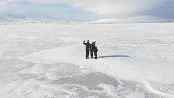 pai mãe e filho juntos acenando para a câmera feliz com sorrisos nas férias de inverno com fundo de paisagem branca deslumbrante video