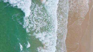 vista aérea de la playa de arena blanca y la textura de la superficie del agua. olas espumosas con cielo. hermosa playa tropical. increíble costa de arena con olas de mar blanco. concepto de naturaleza, paisaje marino y verano. video