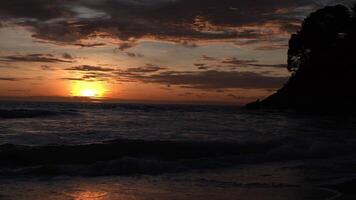 hermosa puesta de sol playa de arena del océano y textura de la superficie del agua. olas espumosas con cielo y nubes. hermosa playa tropical. increíble costa de arena con olas de mar blanco. concepto de naturaleza y verano. video