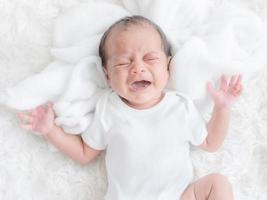 un bebé recién nacido bastardo llorando en la cama porque tenía hambre y estaba enferma foto